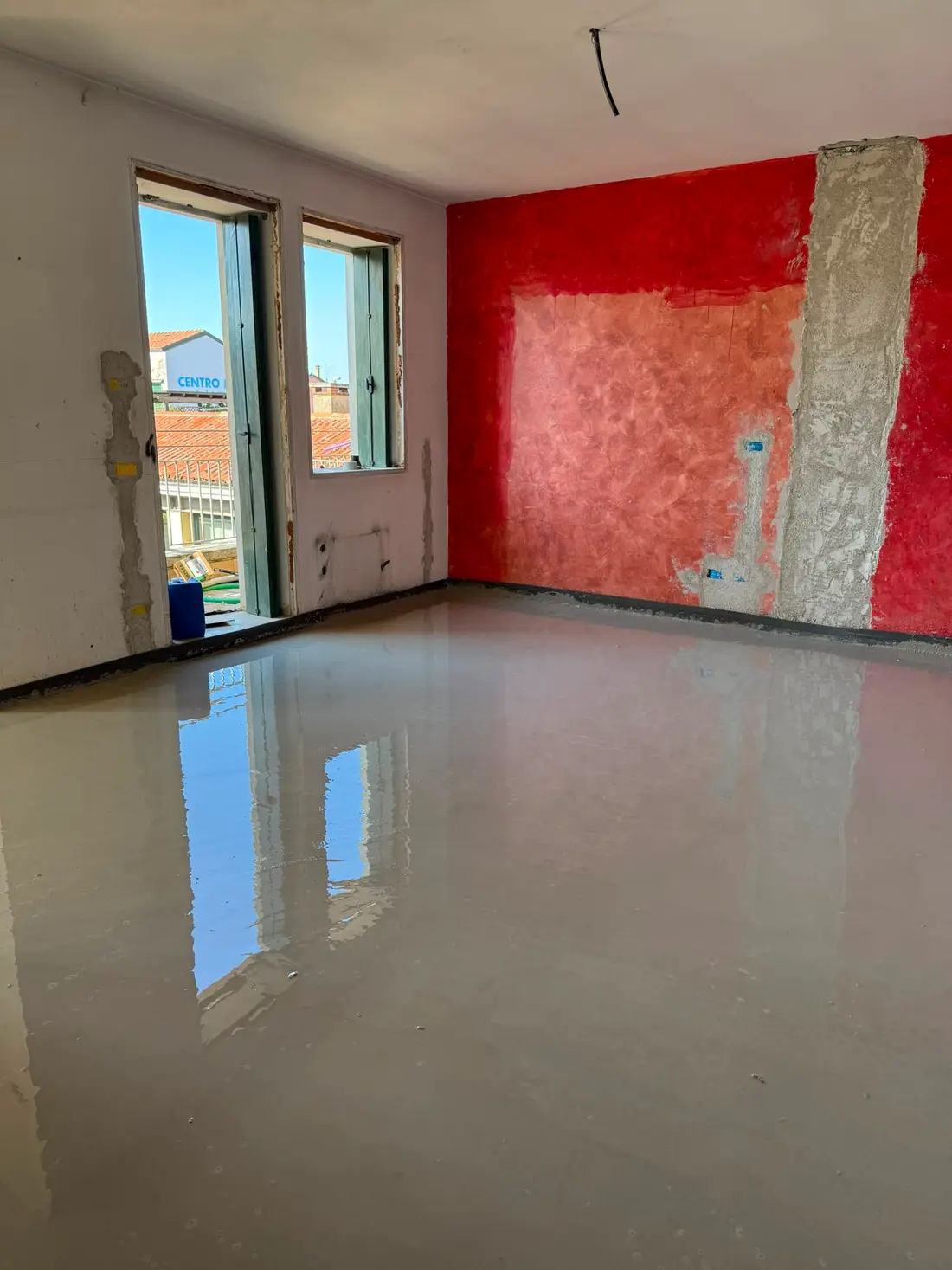 Massetto autolivellante appena colato in un appartamento: la superficie riflette le finestre